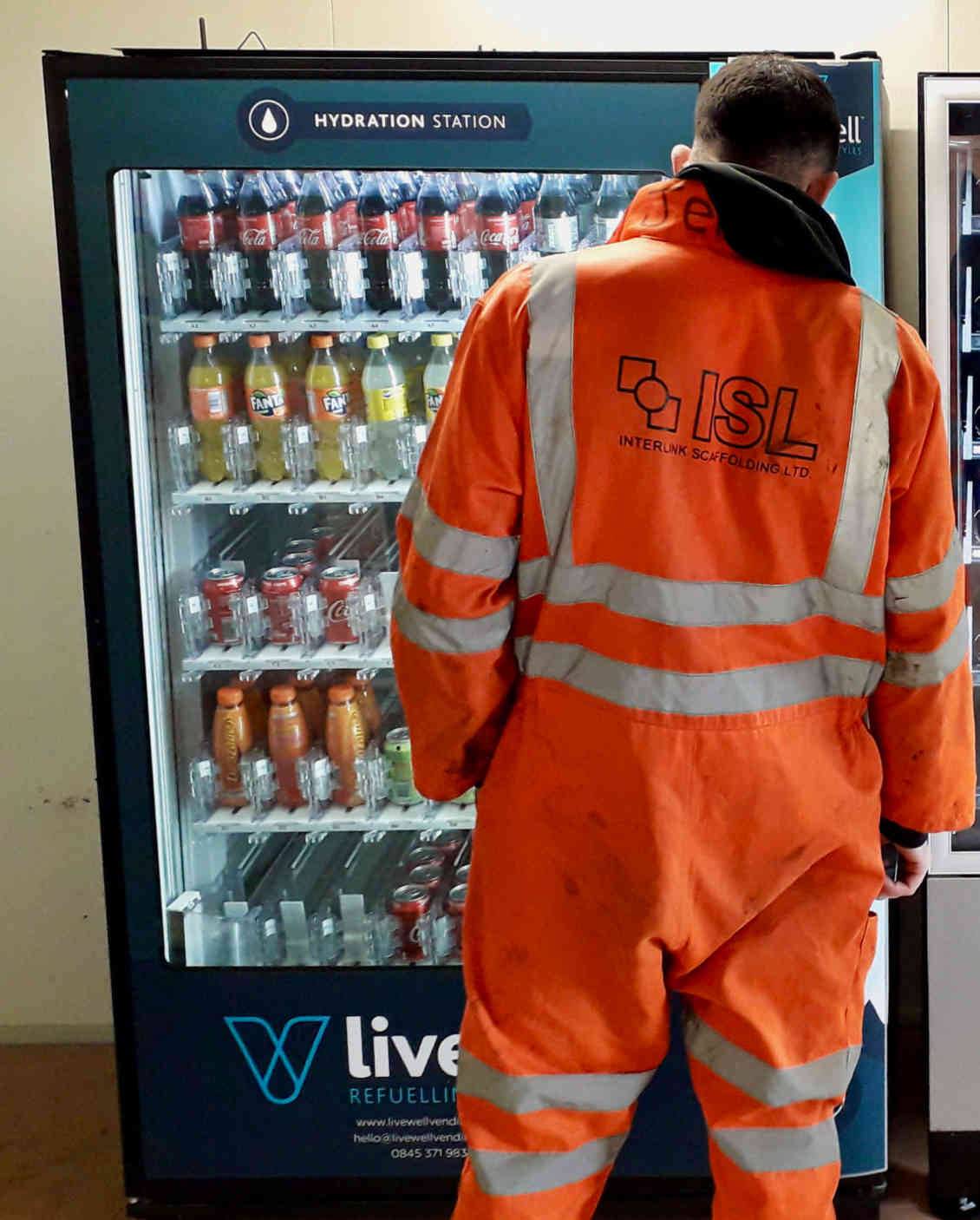 man in overalls choosing a drink from a vending machine