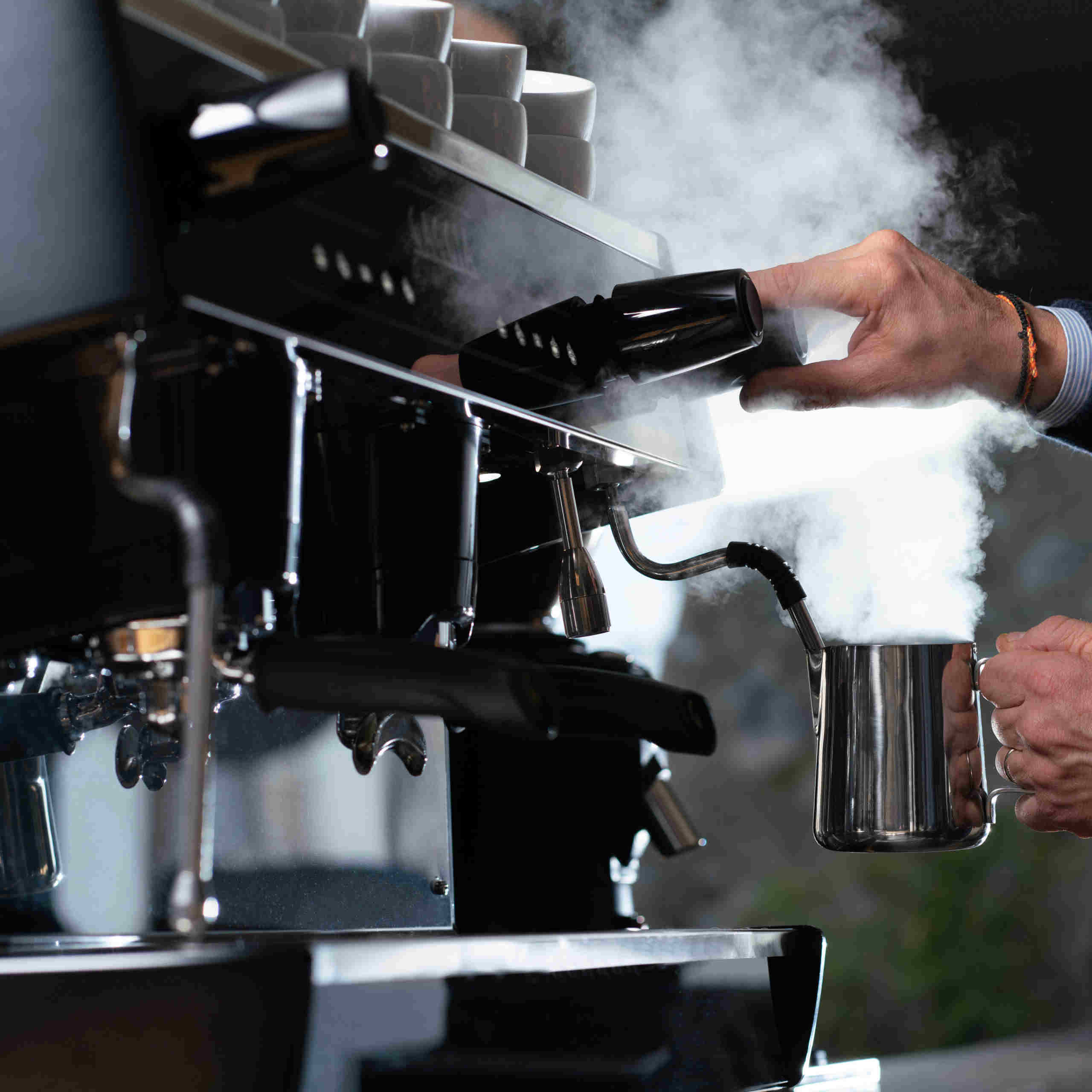 coffee barista steaming milk on a traditional coffee machine